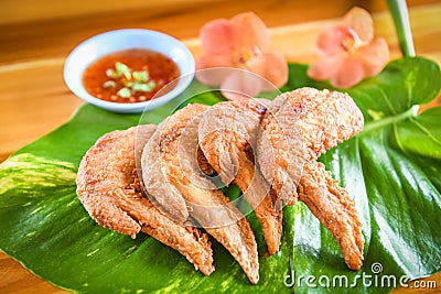 Fried chicken wings served on leaves with sauce top view - crispy chicken wings on wooden table , Thai Food Asian Stock Photo