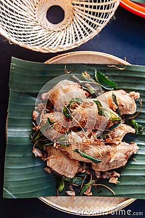 Fried chicken wings in Thai northeastern style with garlic and kaffir lime leaves served on banana leaf Stock Photo