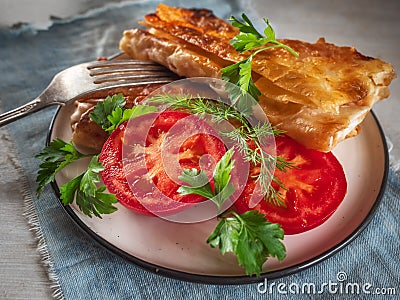 Fried closed sandwich with vegetables on a round plate, close-up Stock Photo