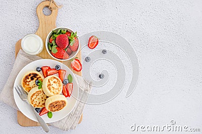 Fried cottage cheese pancakes or syrniki with fresh berries on a white plate with sour cream. Gluten free. Stock Photo