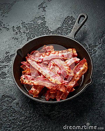 Fried crunchy Streaky Bacon pieces in a cast iron skillet Stock Photo