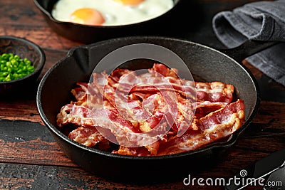 Fried crunchy Streaky Bacon pieces in a cast iron skillet Stock Photo