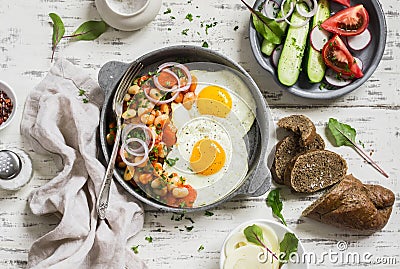 Fried egg, beans in tomato sauce with onions and carrots, fresh cucumbers and tomatoes, homemade rye bread - delicious breakfast Stock Photo