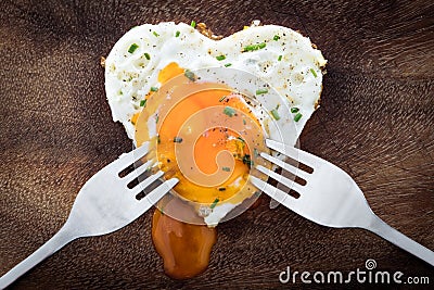 Fried egg with heart shape and two dinner forks, concept love Stock Photo