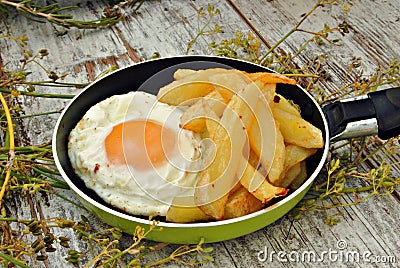 Fried egg with potatoes, served in a pan Stock Photo