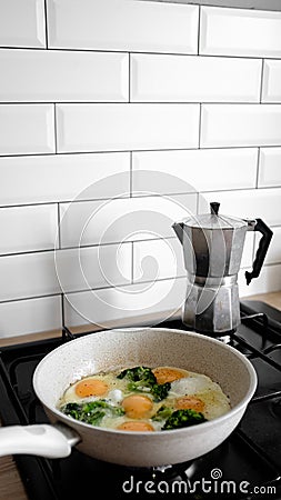 Fried eggs with broccoli in a pan in the kitchen Stock Photo