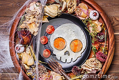 Fried eggs in the shape of a skull and fresh tomatoes. Breakfast in Halloween decorations. Stock Photo