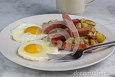 fried eggs with spam sticks and home fries Stock Photo