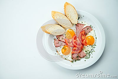 Fried eggs with tomatoes, bread and ham on a white plate isolated on a gray background. Top view with copy space Stock Photo