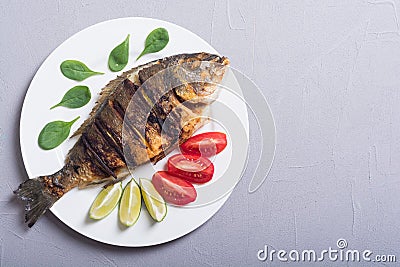 Fried fish dorado with lime , tomatoes and spinach . Sea food Stock Photo