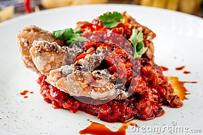 Fried fish fillet on vegetable saute in red sauce Stock Photo