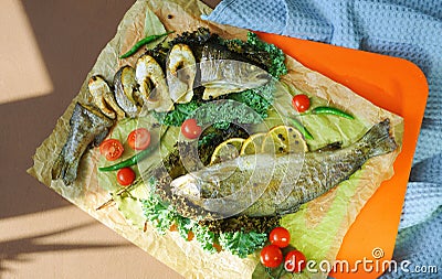 Fried fish with vegetables on colourful background. Lemons, tomatos, pepper, seafood dish. Healthy lifestyle. Restaurant menu. Stock Photo