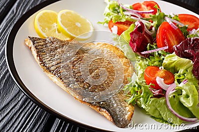 Fried gilt-head fish fillet with a side dish of vegetable salad close-up on a plate. horizontal Stock Photo