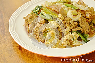 Fried large rice noodles with pork and vegetable in black soy sauce on plate Stock Photo