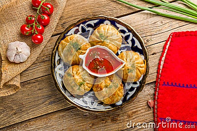 fried manty uzbek cuisine with tomato sauce on wooden background, top view food Stock Photo