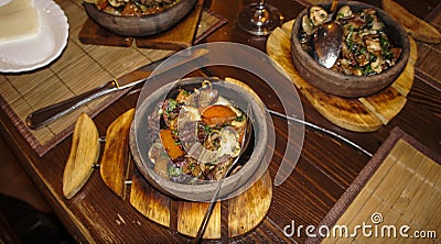 Fried meat and waxes on a dark frying pan on a wooden stand. Stock Photo