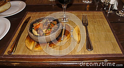 Fried meat and waxes on a dark frying pan on a wooden stand. Stock Photo