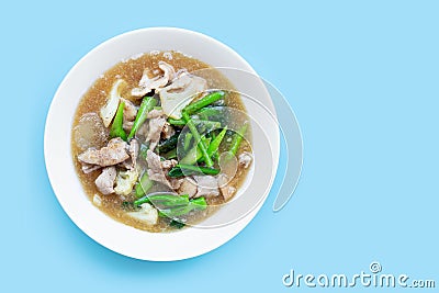 Fried noodle with pork and chinese broccol, cauliflower in white dish on blue background Stock Photo