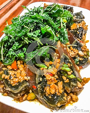 Fried one-thousand-year egg with crispy holy basil leaves and rice dish on a wood table background, Spicy popular traditional dish Stock Photo