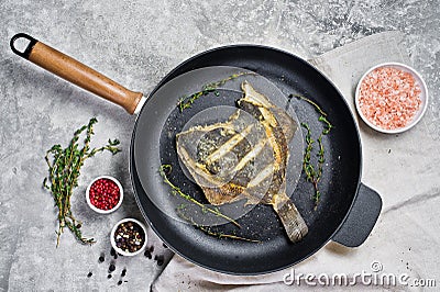 Fried plaice in a pan. Gray background, top view. Stock Photo