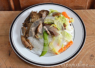 Fried pork entrails with garlic and stir-fried mixed vegetable on rice Stock Photo