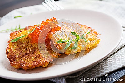 Fried potato pancakes with red caviar and sour cream fritter roesti. Stock Photo