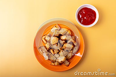 Fried potatoes on orange plate and a little ketchup bowl Stock Photo