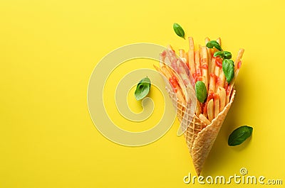 Fried potatoes in waffle cones on yellow background. Hot salty french fries with sauce, basil leaves. Fast food, junk Stock Photo