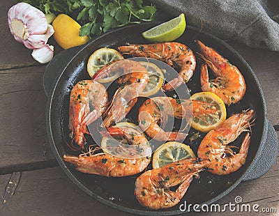 Fried roasted shrimps in frying pan with lemon greens parsley garlic Stock Photo
