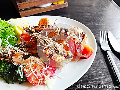 Fried roasted shrimps in plate with lemon and green salat Stock Photo