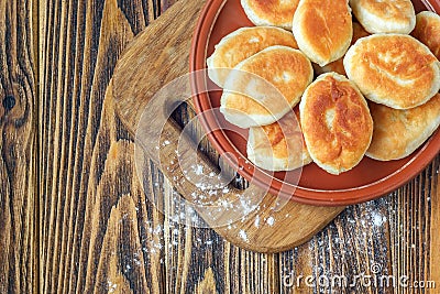 Fried russian pastry pirozhki on wooden background. Stock Photo