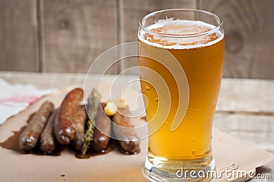 Fried sausages and mug of cold beer on a wooden table. Top view Stock Photo