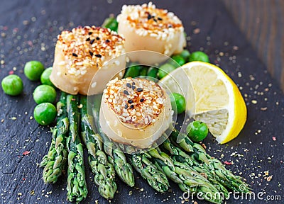 Fried scallops with sesame seeds, asparagus, lemon and green peas Stock Photo