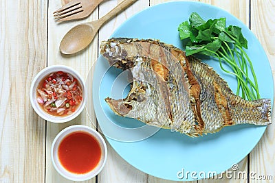 Fried sea fish in dish on wooden floor and Thai spice sauce. Stock Photo