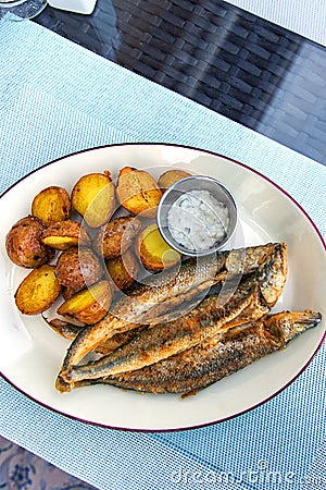 Fried smelt with boiled potatoes and mushroom sauce on white plate. Delicious rustic lunch Stock Photo