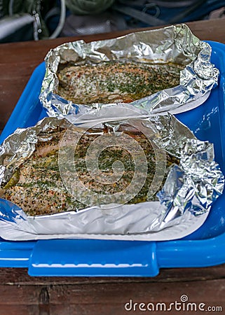 Fried trout in foil on a blue plastic tray Stock Photo