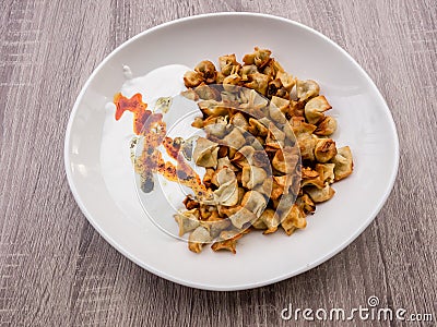 Fried Turkish Manti with red pepper, tomato sauce, yogurt and mint. Plate of traditional Turkish food. Top view Stock Photo