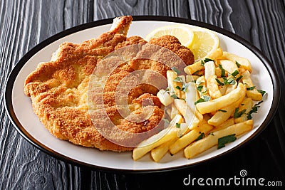 Fried veal cutlet Milanese with lemon and French fries close-up Stock Photo