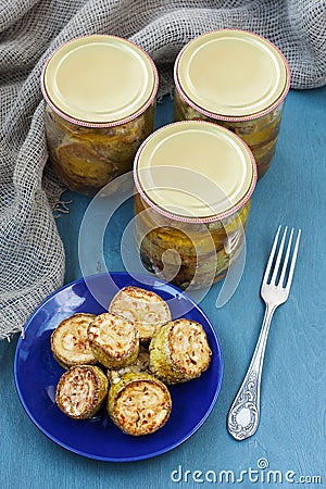 Fried zucchini slices pickled in olive oil with herbs and filled in a canning jar, top view Stock Photo