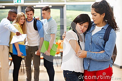 Friend Comforting Victim Of Bullying At School Stock Photo