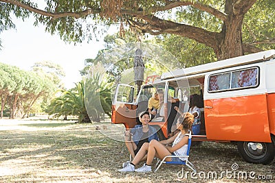 Friend sitting by camper van at campsite Stock Photo