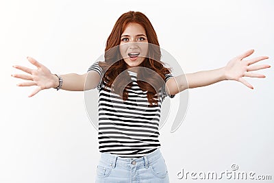 Friendly amazed cute redhead caucasian girl in striped t-shirt extend arms sideways, move towards camera to give hug Stock Photo