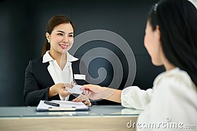 Friendly Asian female receptionist greeting and welcoming a customer with beautiful smile Stock Photo