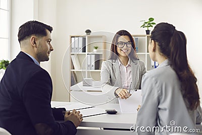 Friendly bank worker giving pen to sign contract promising good deal to client Stock Photo