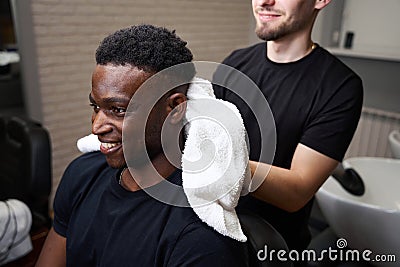 Friendly barber dries clients hair with soft towel Stock Photo