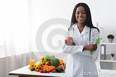 Friendly black woman dietician with apple and tape Stock Photo