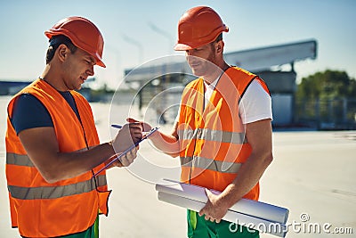 Friendly builder talking and his colleague making notes Stock Photo
