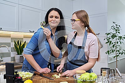 Friendly cheerful family, portrait of mom and teenage daughter, with green parrot Stock Photo