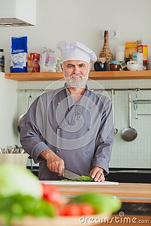 Friendly chef preparing vegetables in his kitchen Stock Photo