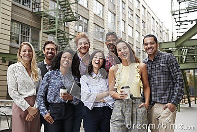 Friendly coworkers laugh to camera outside their workplace Stock Photo